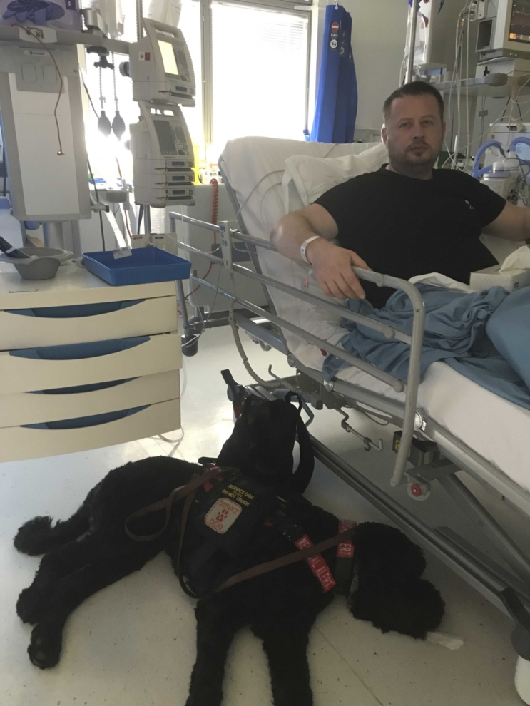 Jonathon Sheldon, 45, tuổi với chú chó dịch vụ Teddy trong bệnh viện (Caters News)