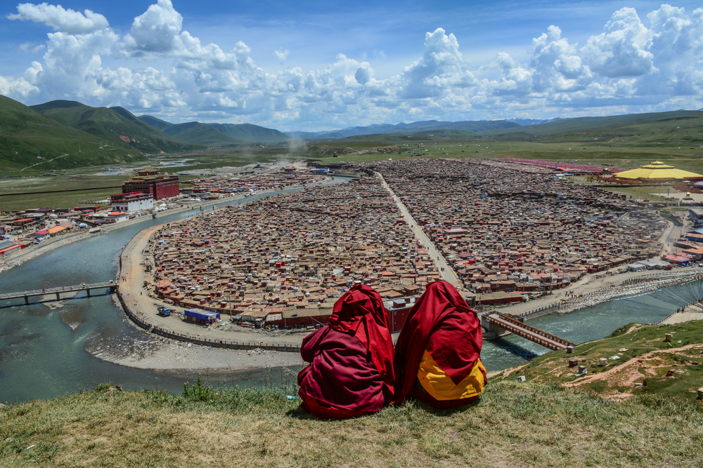 Các nhà sư Tây Tạng ngồi trên đồi và nhìn vào tu viện Phật giáo Tây Tạng Yarchen Gar ở Tứ Xuyên, Trung Quốc. (Phuong D. Nguyen / Shutterstock)